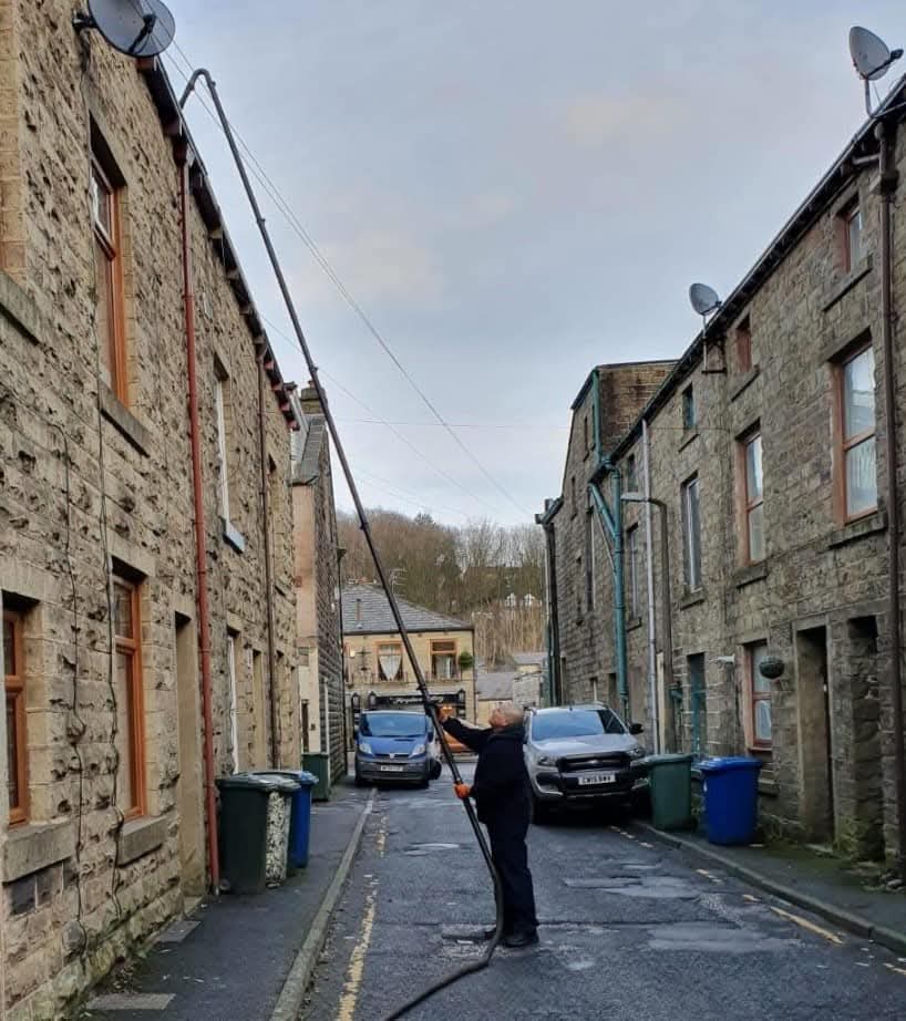 Paul, owner of PW Gutter Cleans, cleaning gutters with a pole system in Haslingden